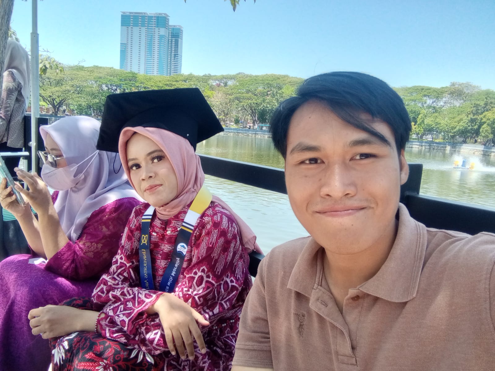 Anggraeni mengenakan toga saat wisuda, bersama Candra